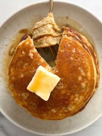 Stack of buttermilk protein pancakes topped with butter and maple syrup