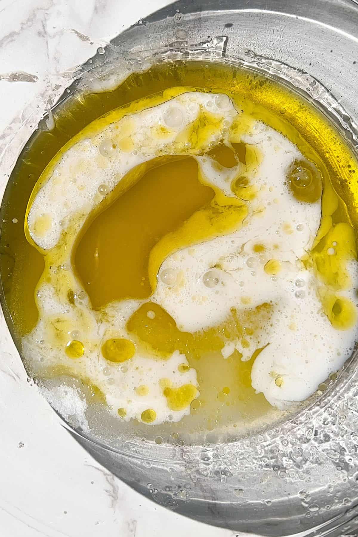 Adding the remaining wet ingredients to the olive oil and granulated sugar in a bowl.