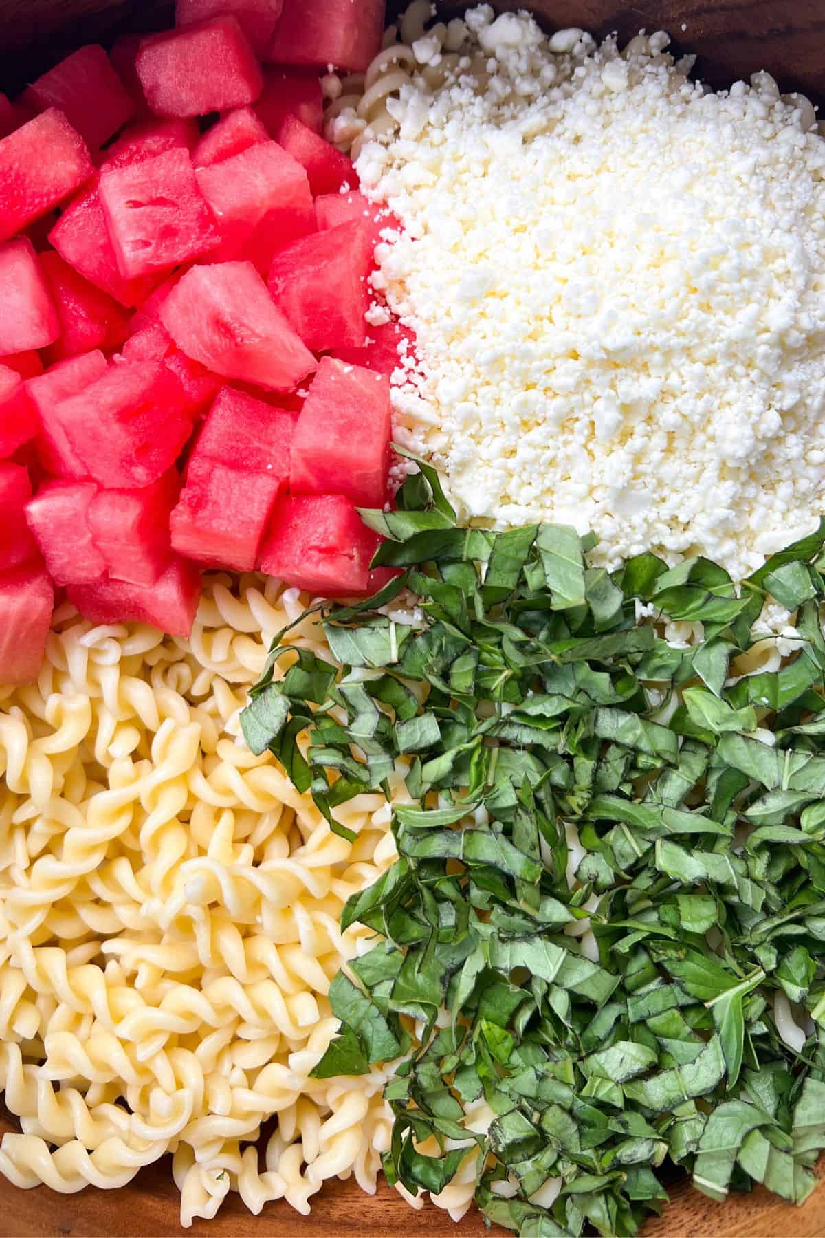 Watermelon Basil Feta Salad with pasta in a large mixing bowl.