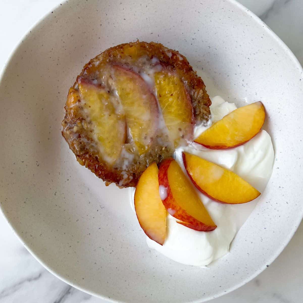 Peach Baked Oatmeal with Cream in a bowl topped with fresh peaches.
