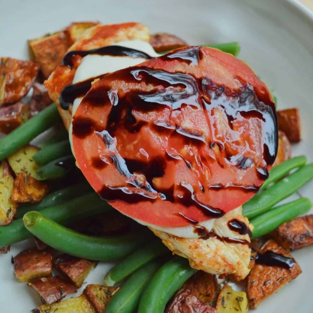 baked chicken caprese on top of vegetables and drizzled with a balsamic glaze