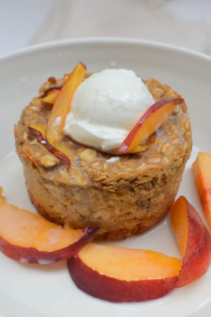 peaches and cream baked oats topped with greek yogurt and fresh peaches