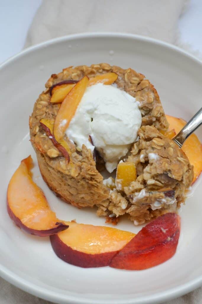 peaches and cream baked oatmeal being scooped with a spoon