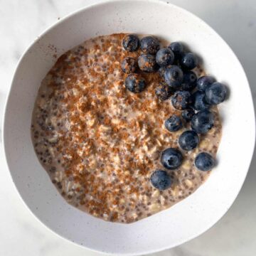 Cinnamon overnight oats served in a bowl and topped with cinnamon and fresh blueberries.