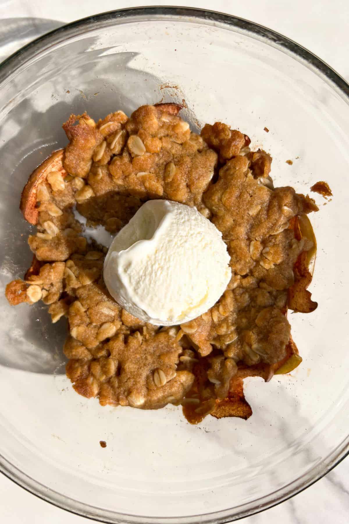 Baked apple crumble for two topped with vanilla ice cream.