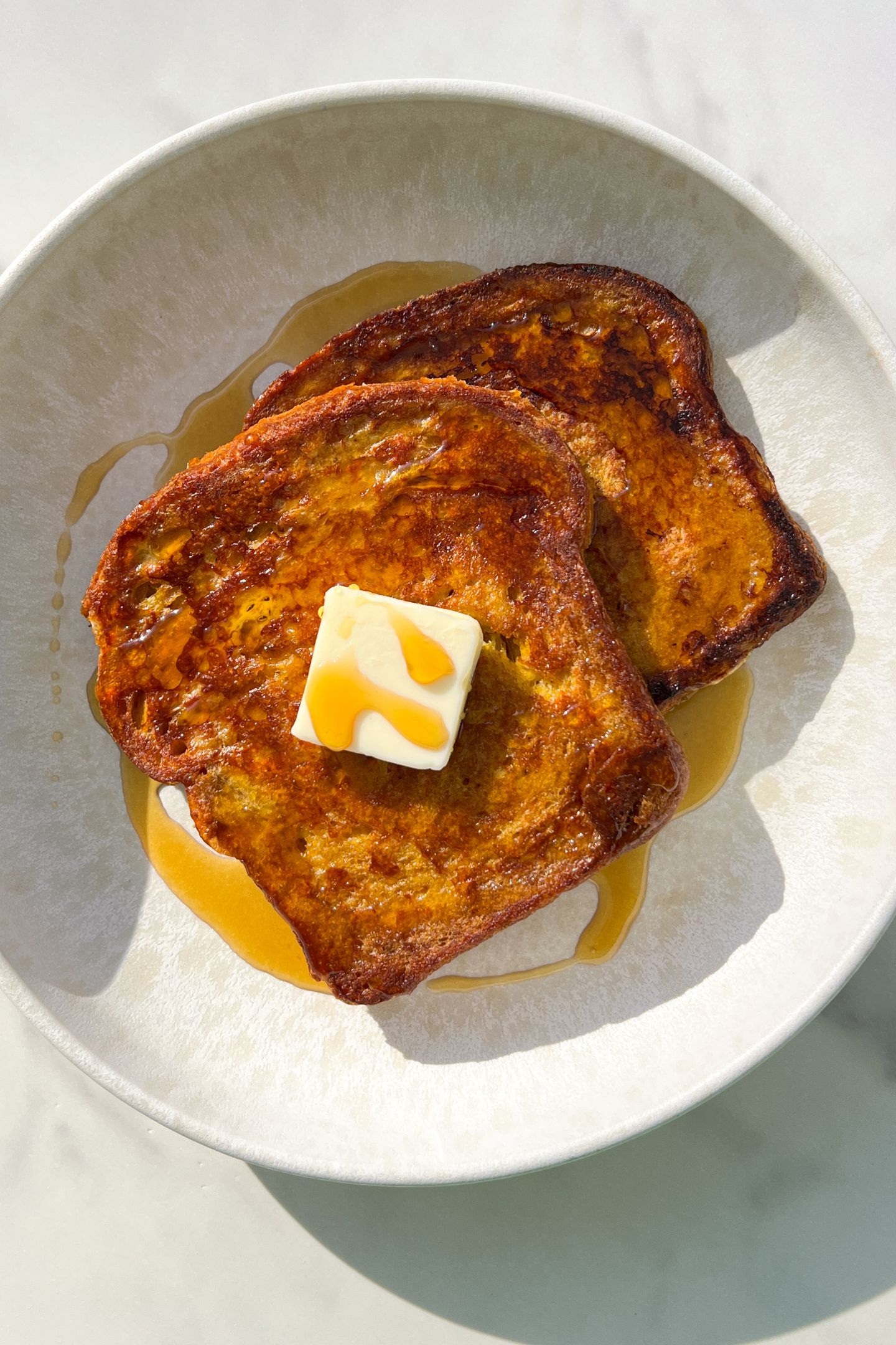 Slices of Healthy French Toast on a plate with butter and maple syrup.