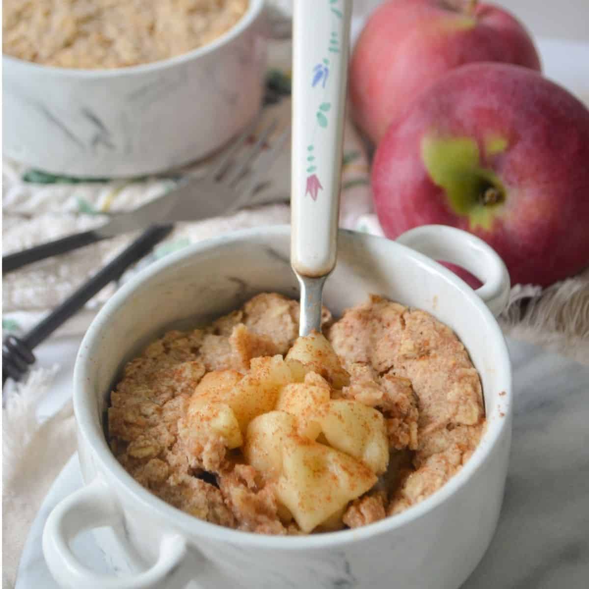 single serving apple crisp with a spoon scooping some crisp out of the ramekin