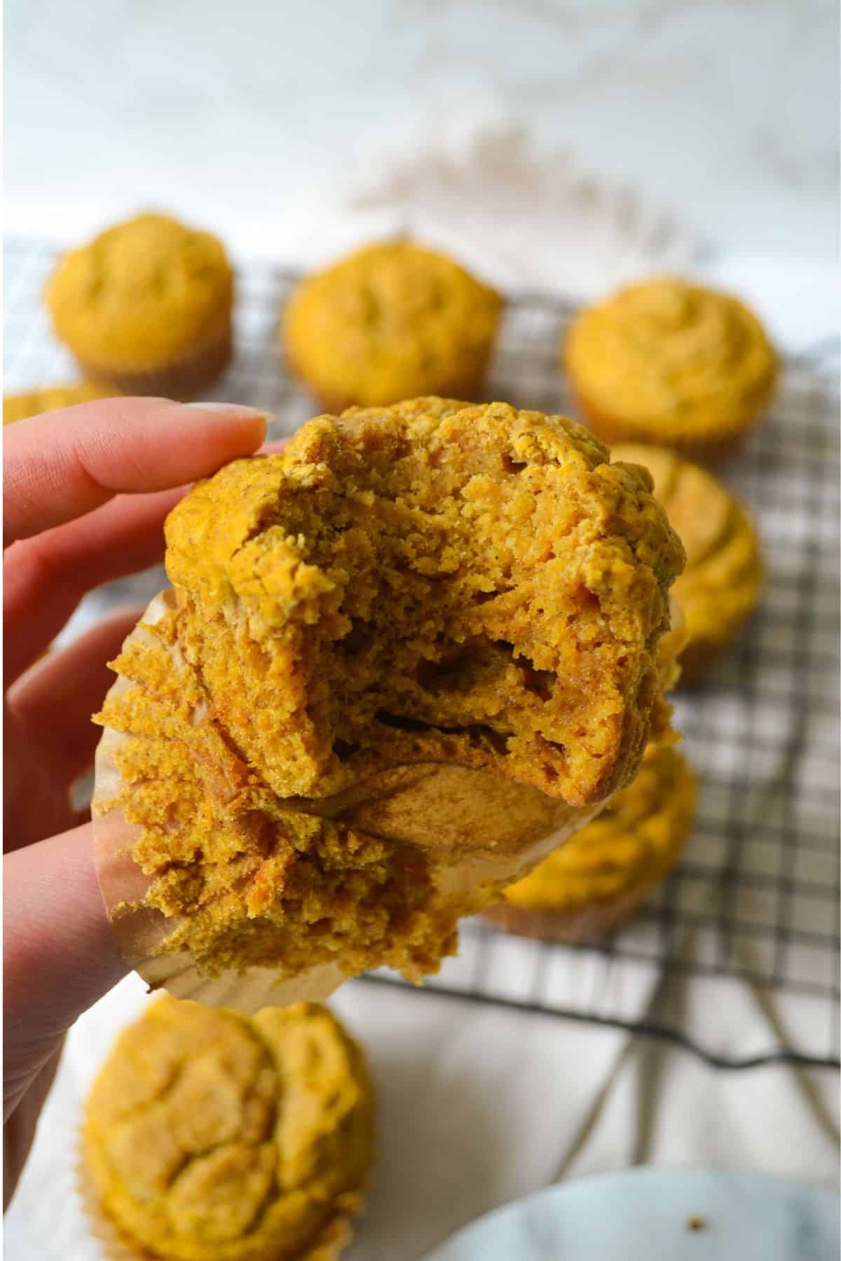 Holding a pumpkin muffin with a bite taken out of it.