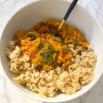 potato, spinach and chickpea curry served in a bowl with brown rice