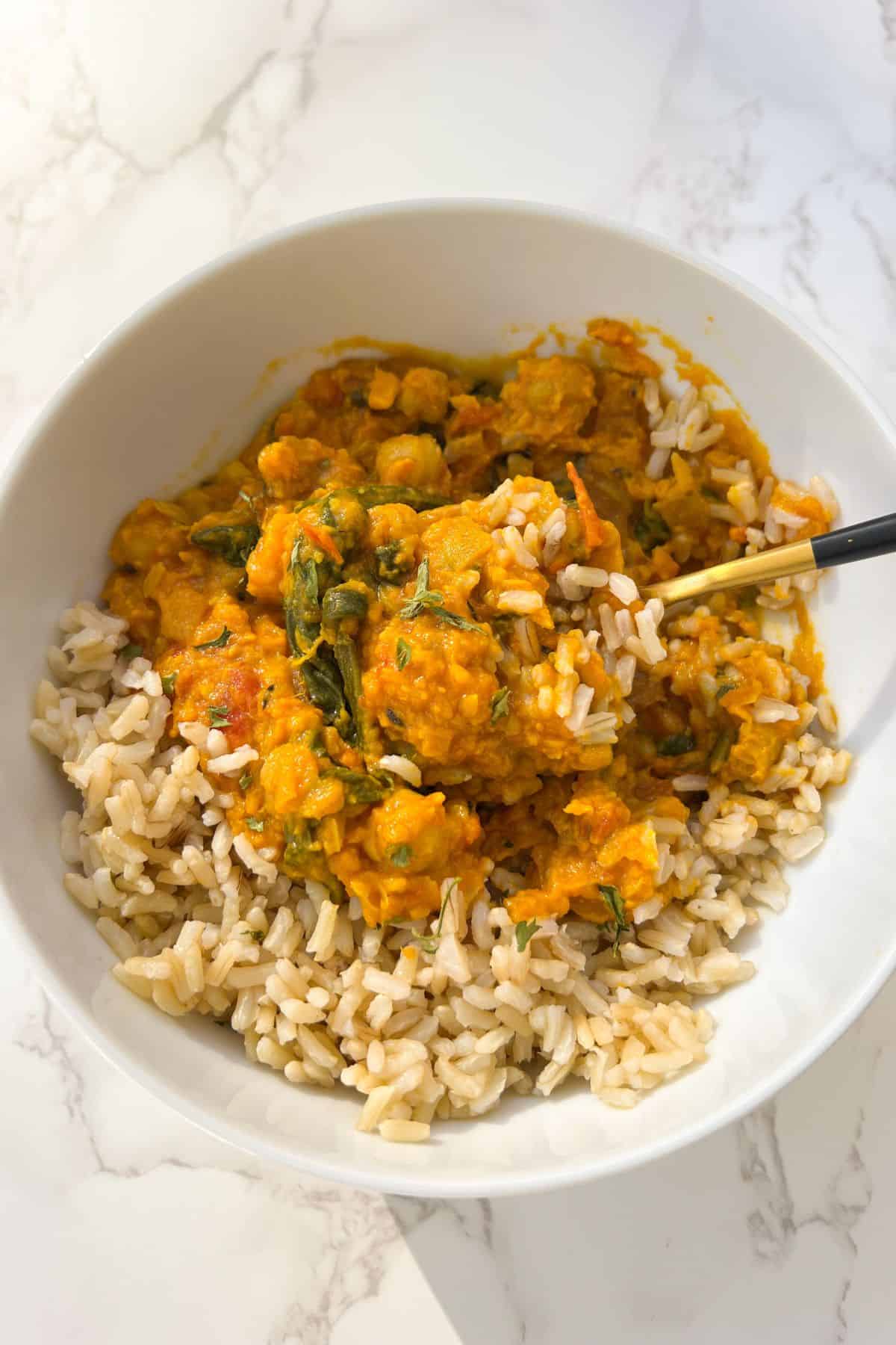 potato, spinach and chickpea curry served with rice in a bowl