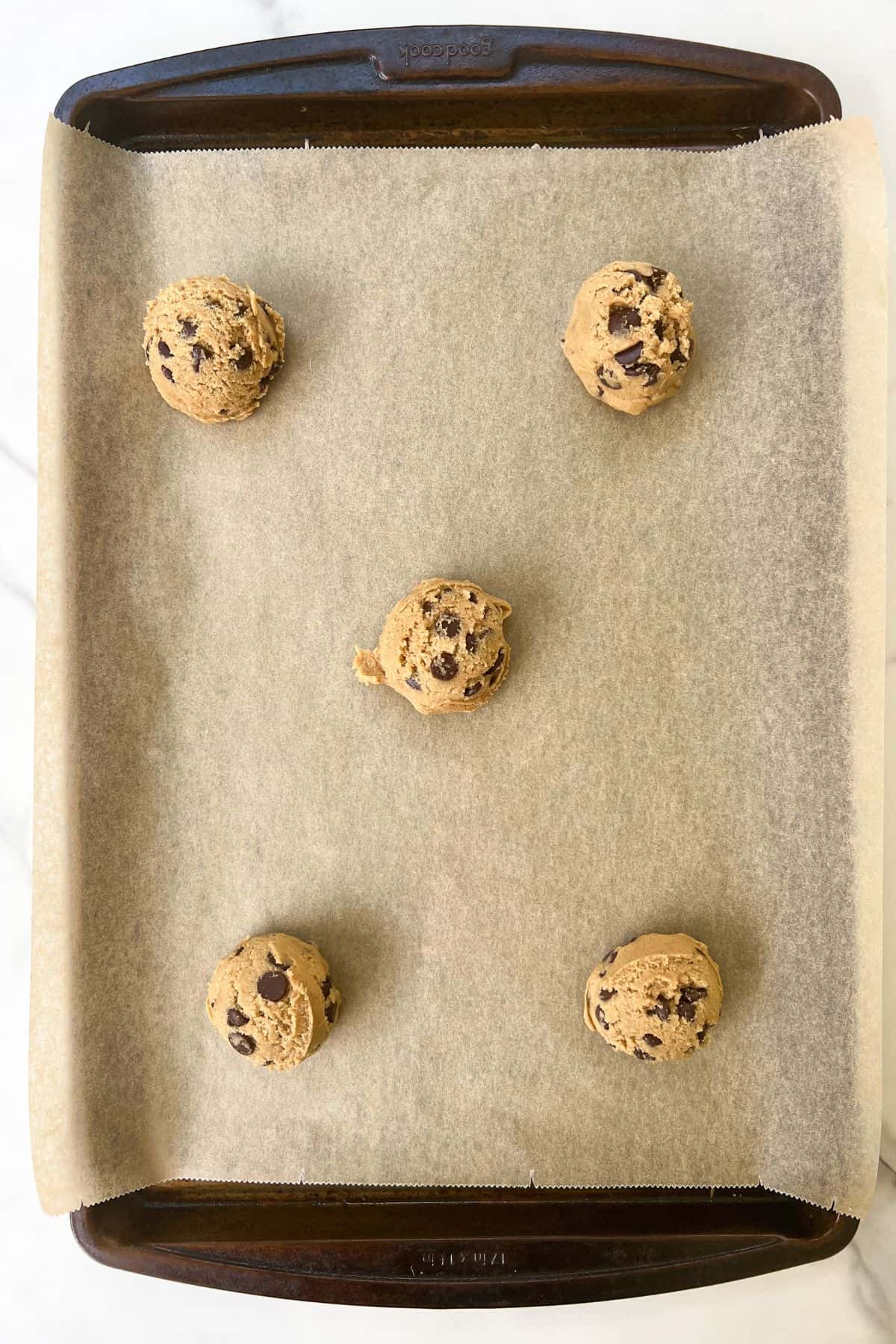Scoop the cookie dough into even sized balls and place spread out on a baking sheet lined with parchment paper.