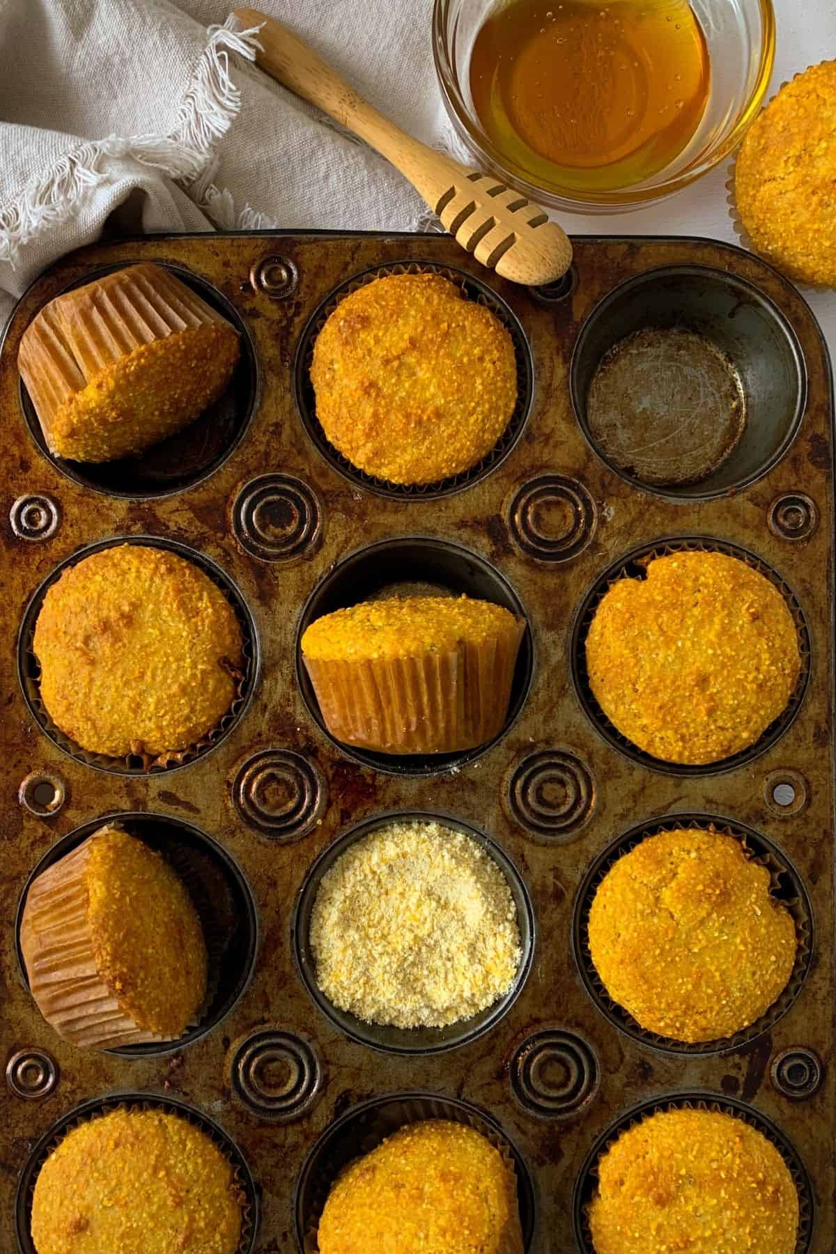 cornbread muffins in a muffin tin with honey