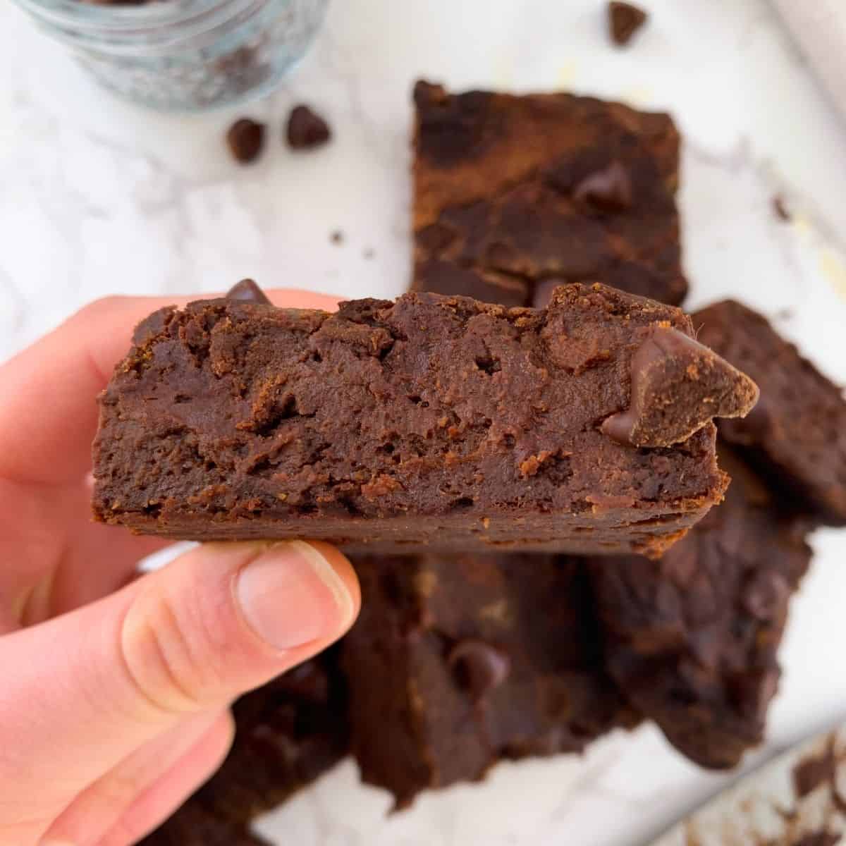 holding a brownie sideways to show the inside, fudgy and moist