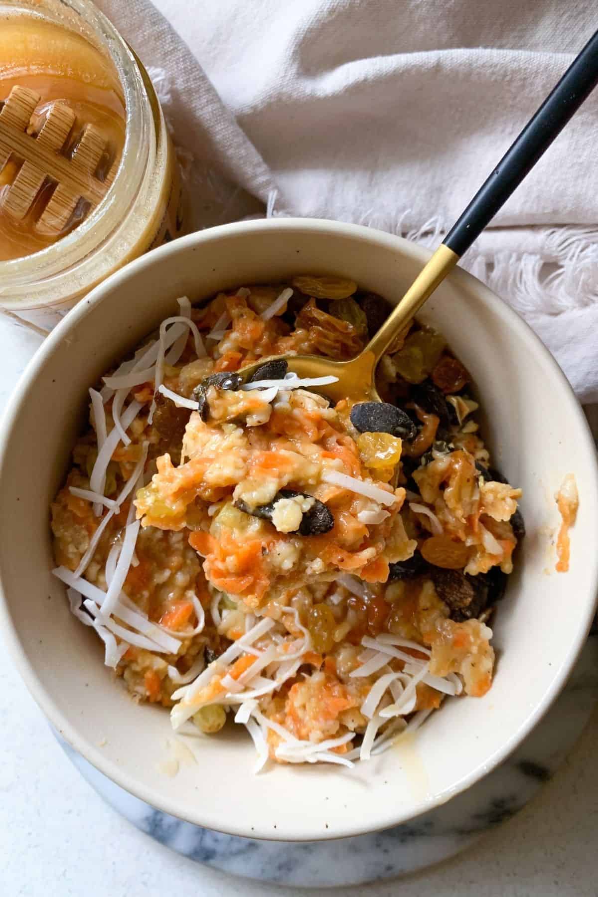 vegan carrot cake oatmeal topped with coconut, pumpkin seeds and golden raisins