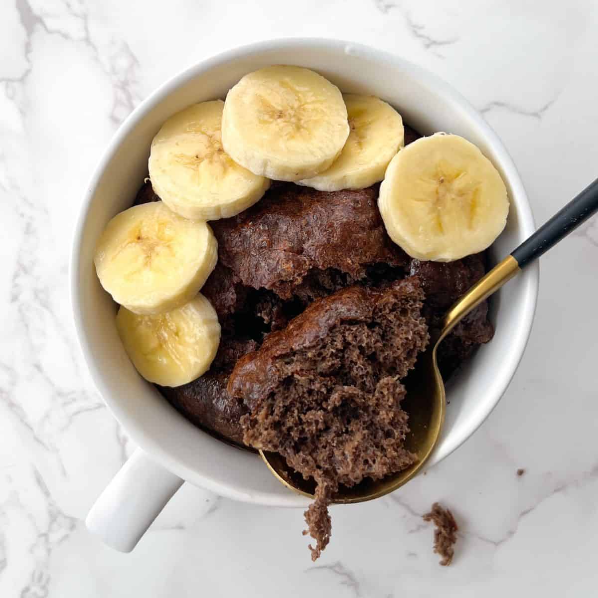 Eating a chocolate protein mug cake in a mug and topped with banana slices
