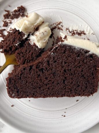 Eating a slice of Mini Chocolate Cake with Cream Cheese Frosting with a fork.