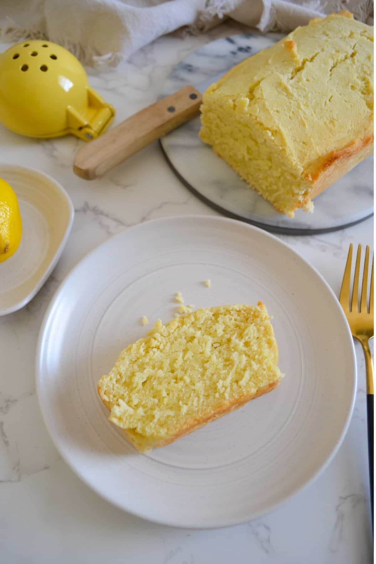 slice of lemon bread on a plate next to the loaf