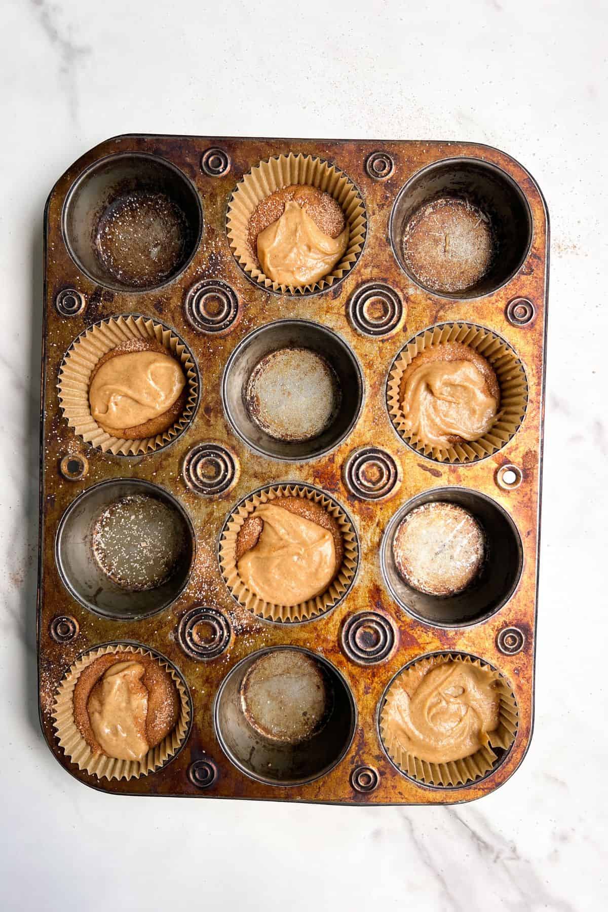 Cinnamon Streusel Muffin Batter poured into the muffin holders.