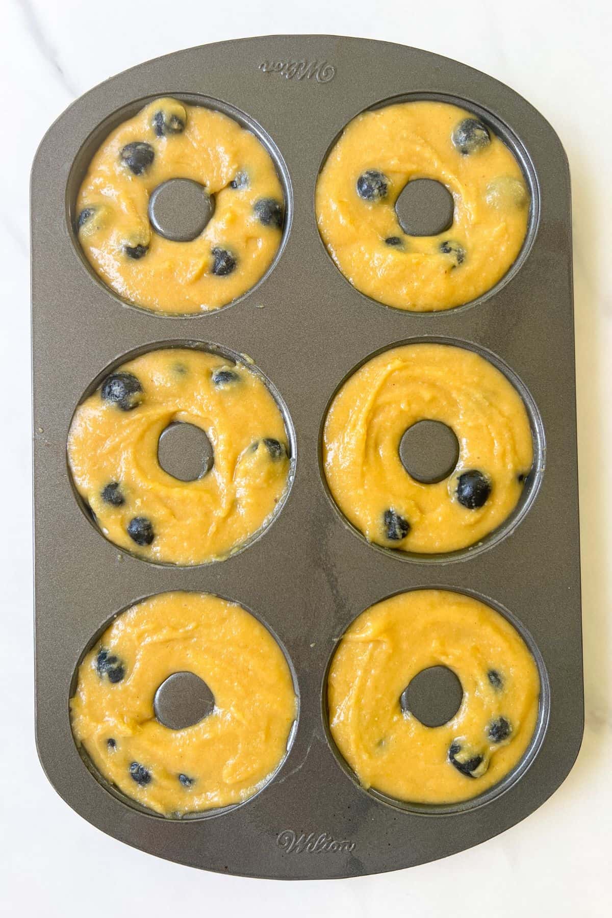 Blueberry cake donut batter poured into a donut pan.