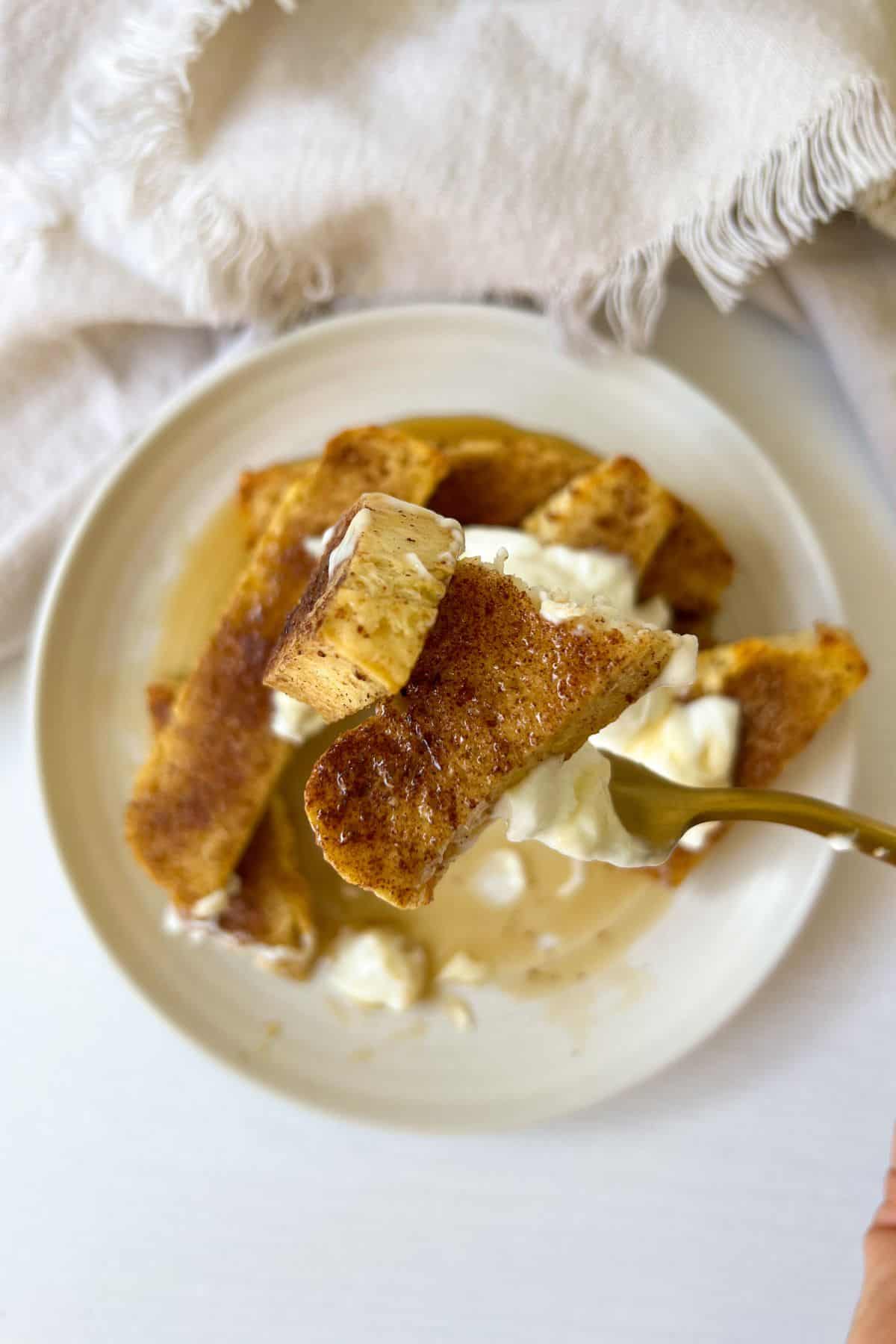 cutting french toast sticks topped with greek yogurt and honey