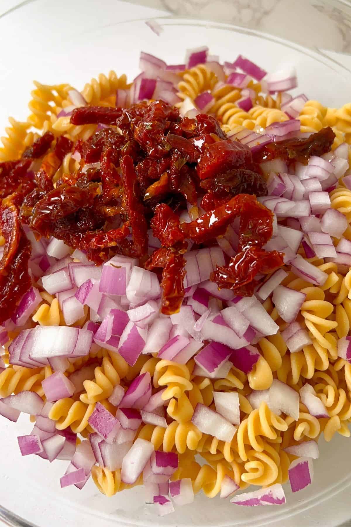 cooked pasta topped with red onion and sundried tomatoes