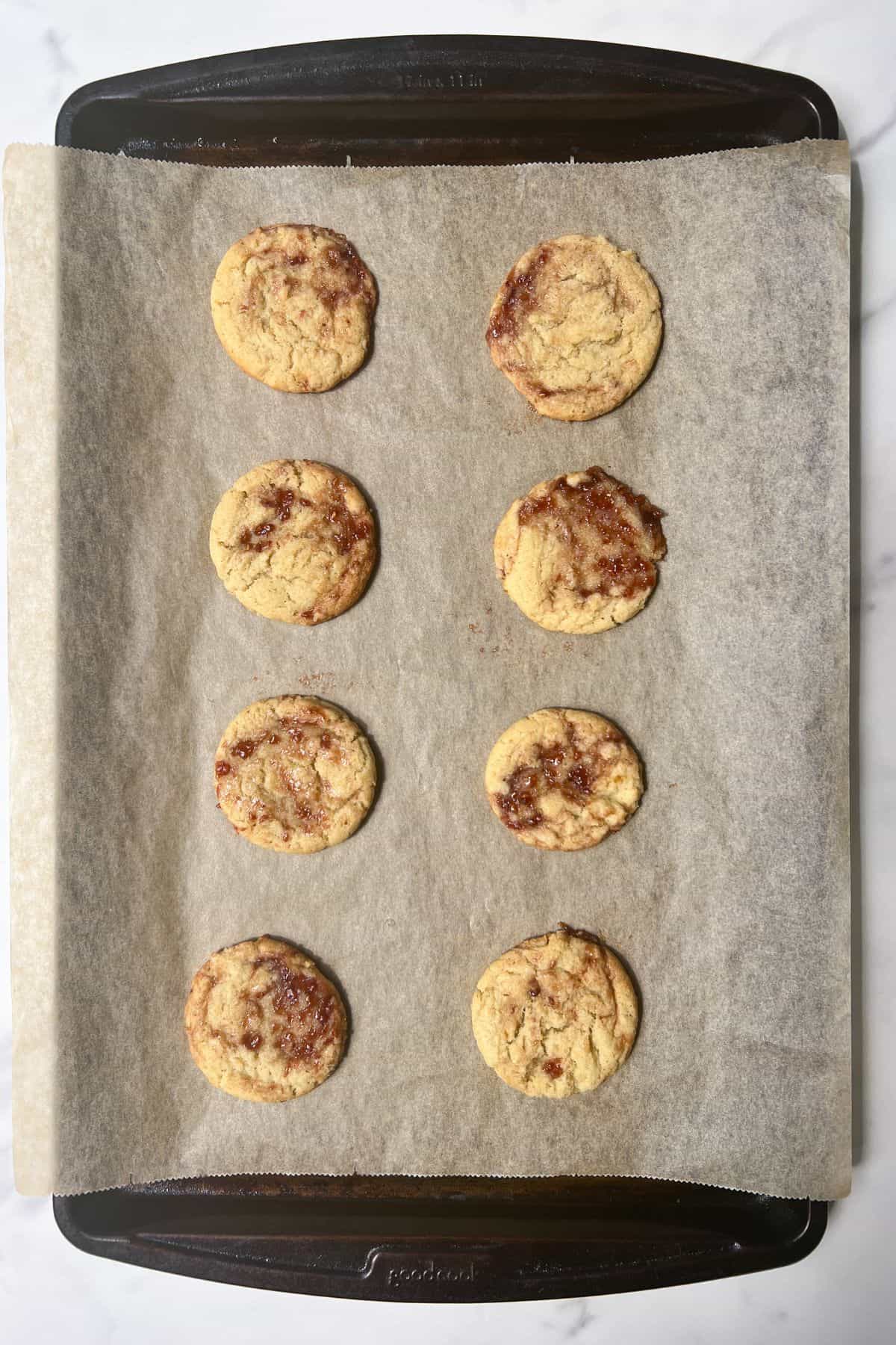 Strawberry Jam Cookies baked and cooling on a baking sheet.