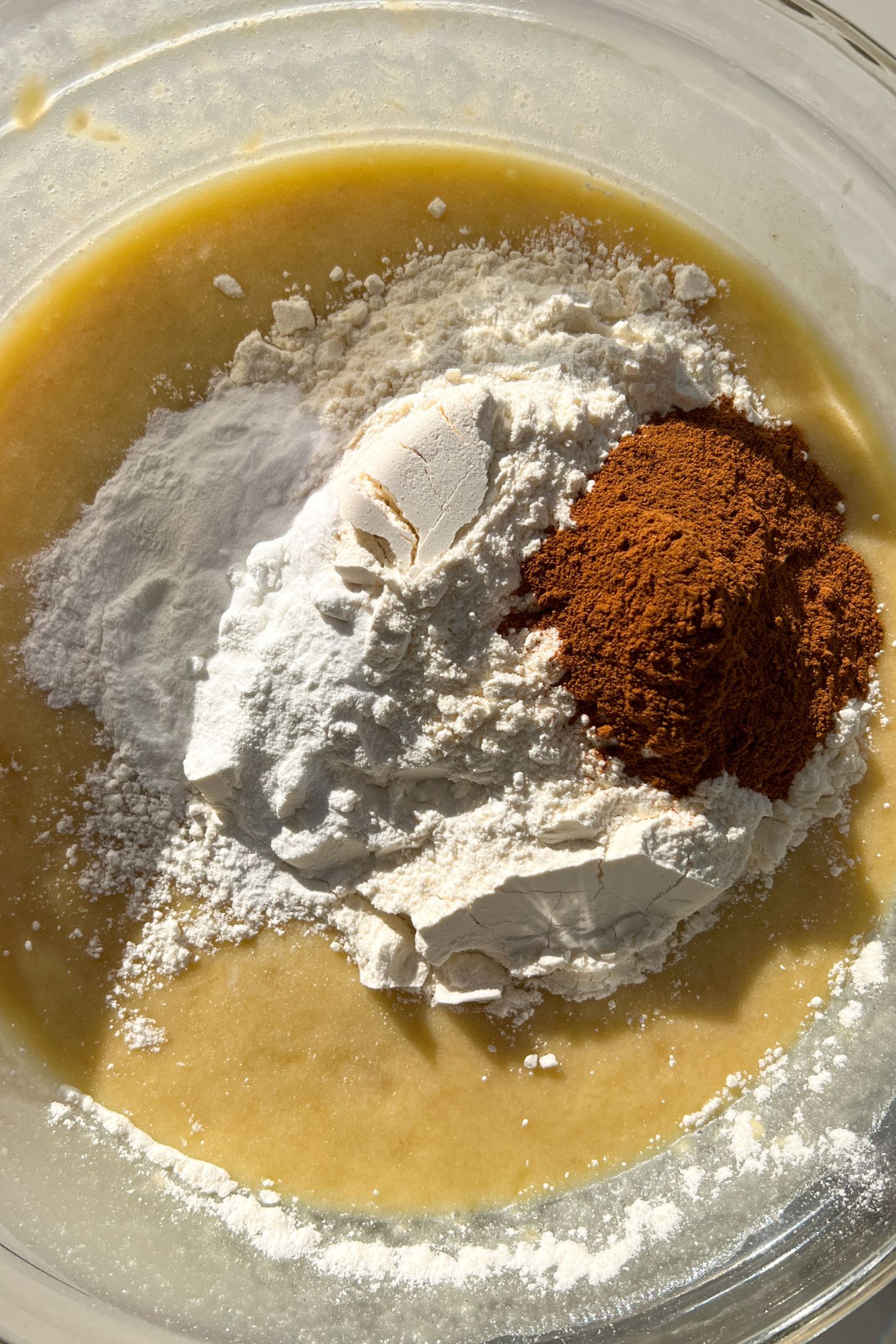 Wet ingredients mixed together in a large mixing bowl with the dry ingredients on top.