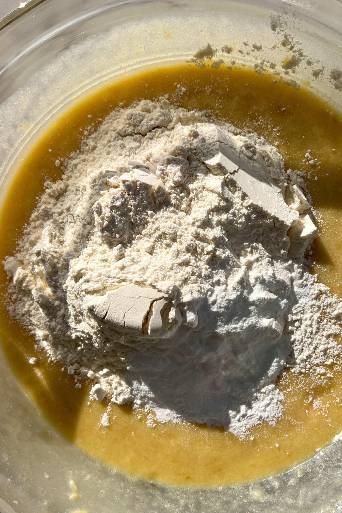Wet ingredients mixed together in a large mixing bowl with flour on top.