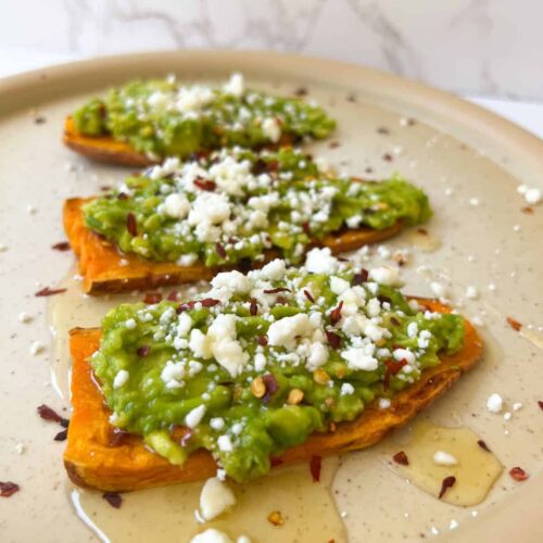 protein avocado toast on sweet potato slices and topped with feta cheese, red pepper flakes and honey