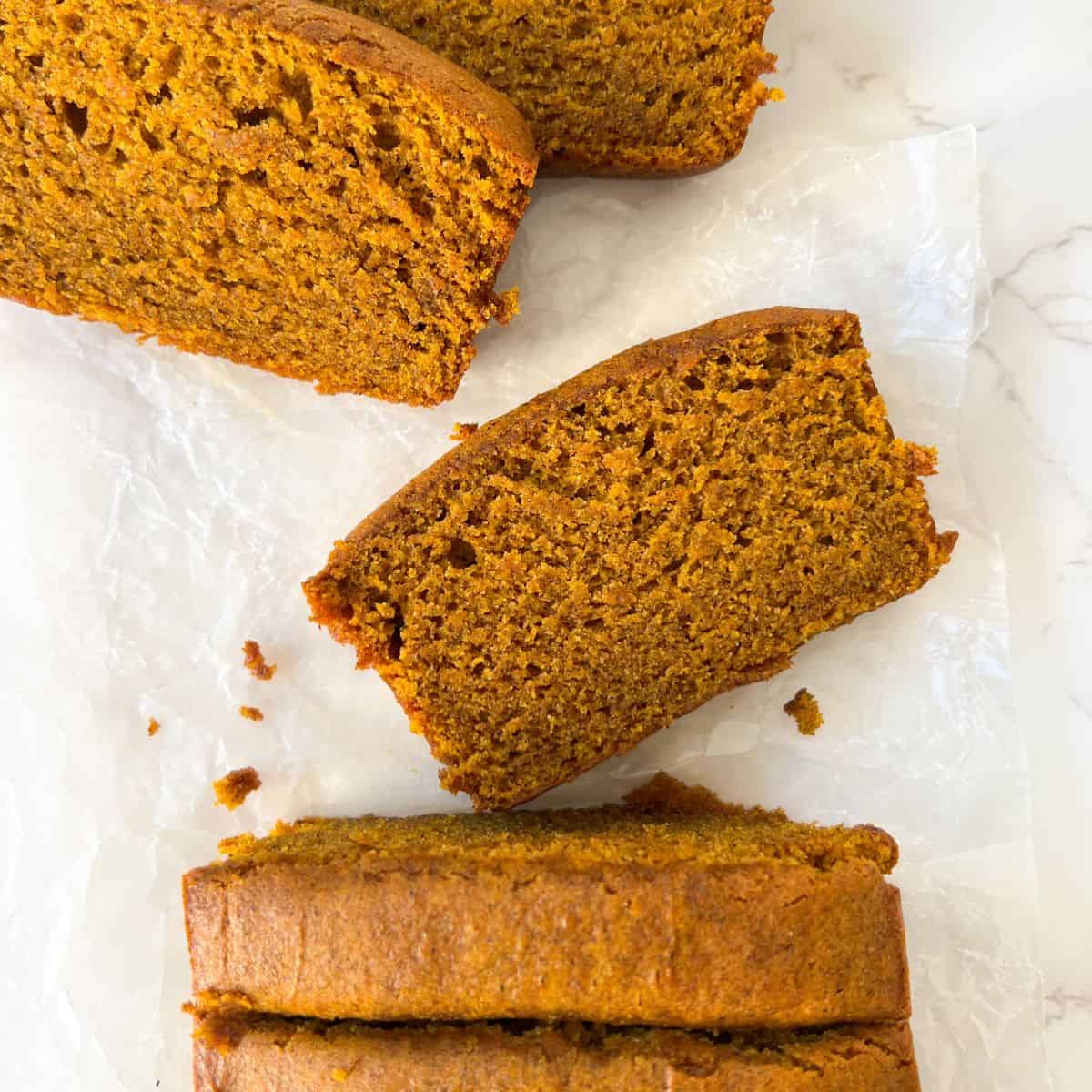 slices of buckwheat pumpkin bread flat on the table in front of the loaf