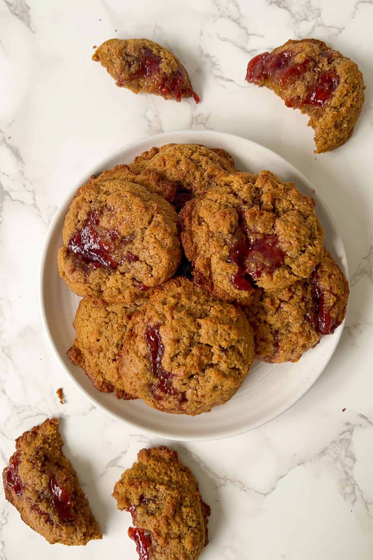 peanut butter jam drop cookies on a plate surrounded by broken cookies