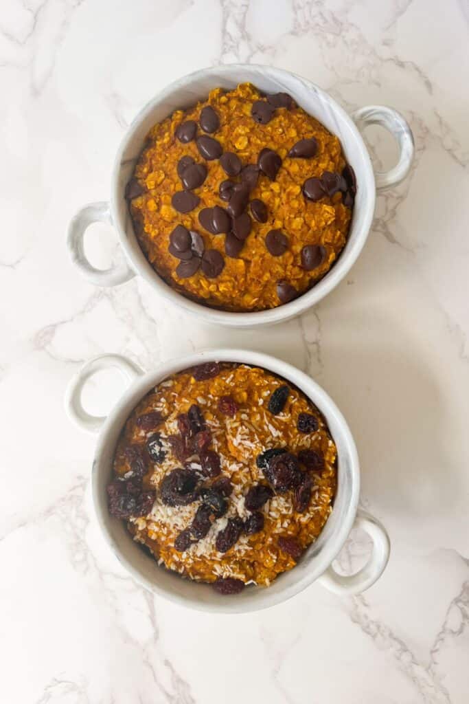 pumpkin baked oats ready to eat in individual ramekins and topped with chocolate chips, raisins and shredded coconut