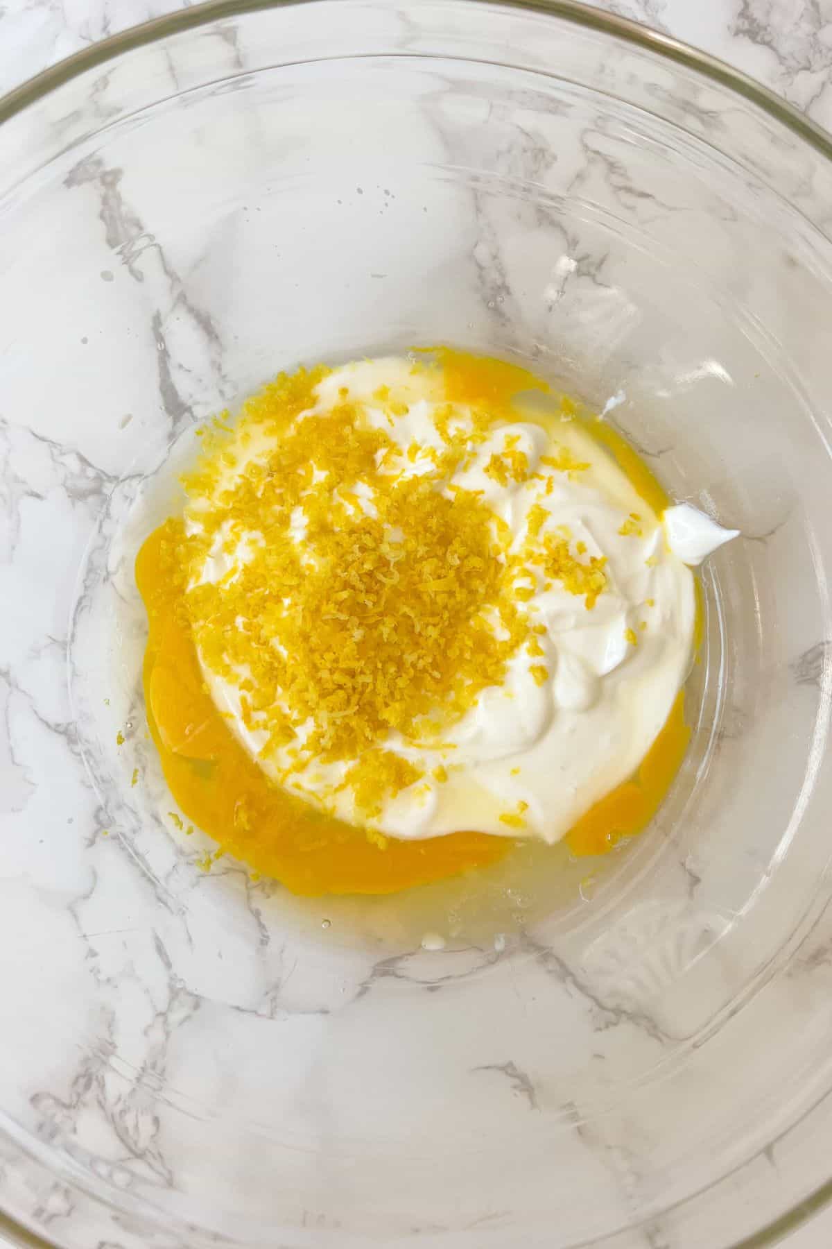 lemon zest with yogurt and eggs in a mixing bowl