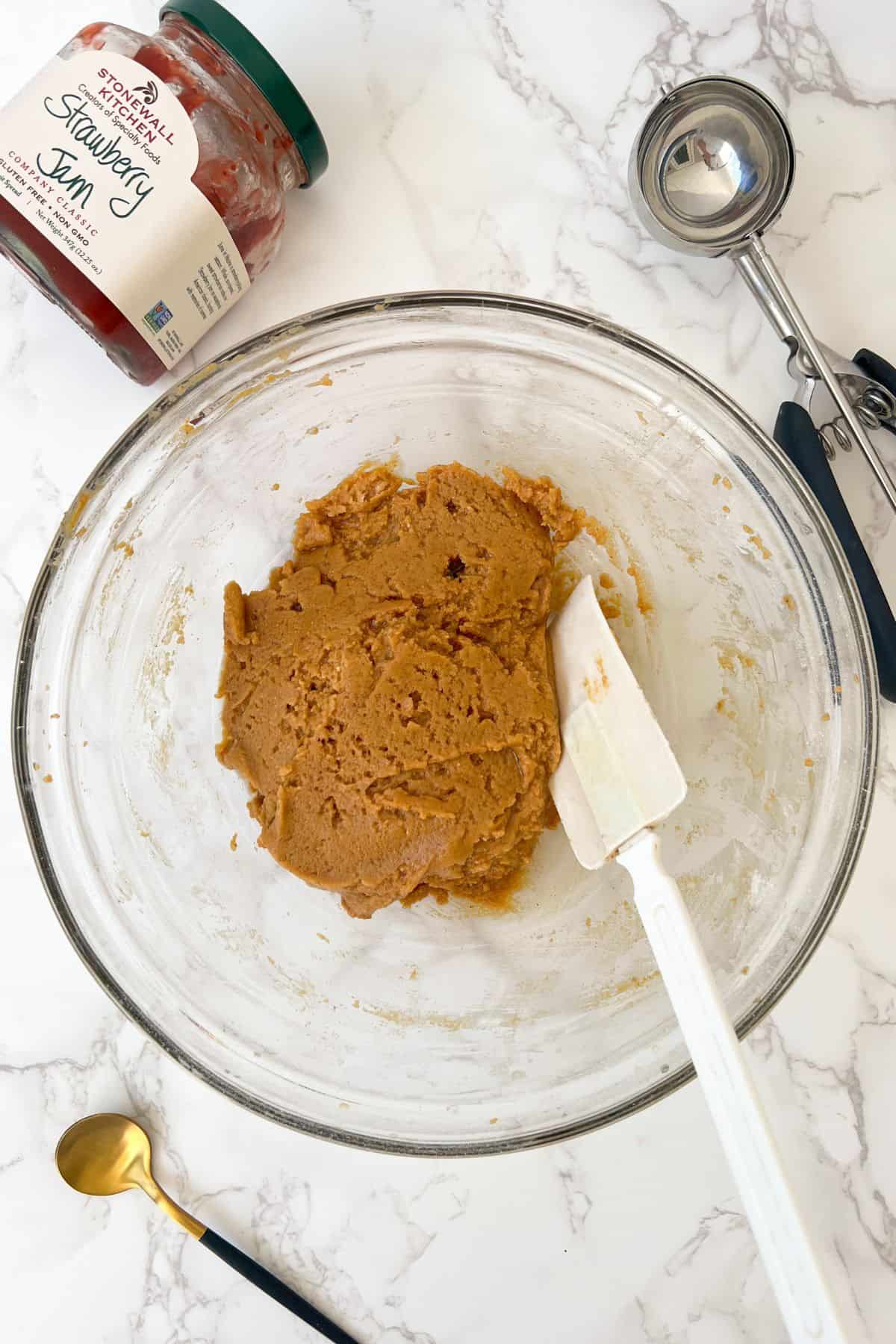 peanut butter cookie dough batter in a bowl before adding in the jam