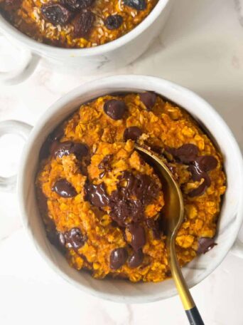 Pumpkin Spice Baked Oats without eggs in a ramekin and topped with chocolate chips.