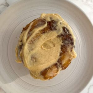 cinnamon roll with buttercream frosting on a plate