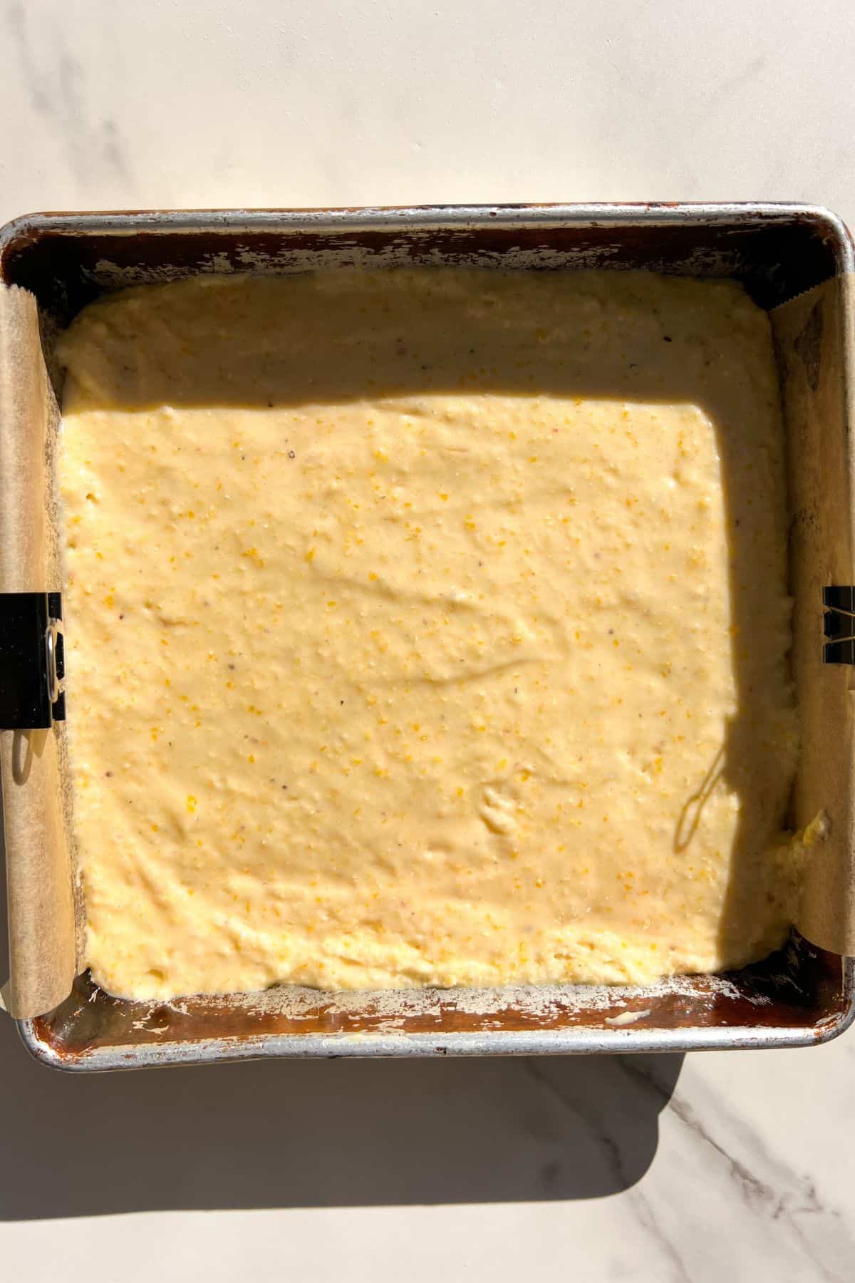 Gluten-free cornbread batter to an 8x8 square pan lined with parchment paper.