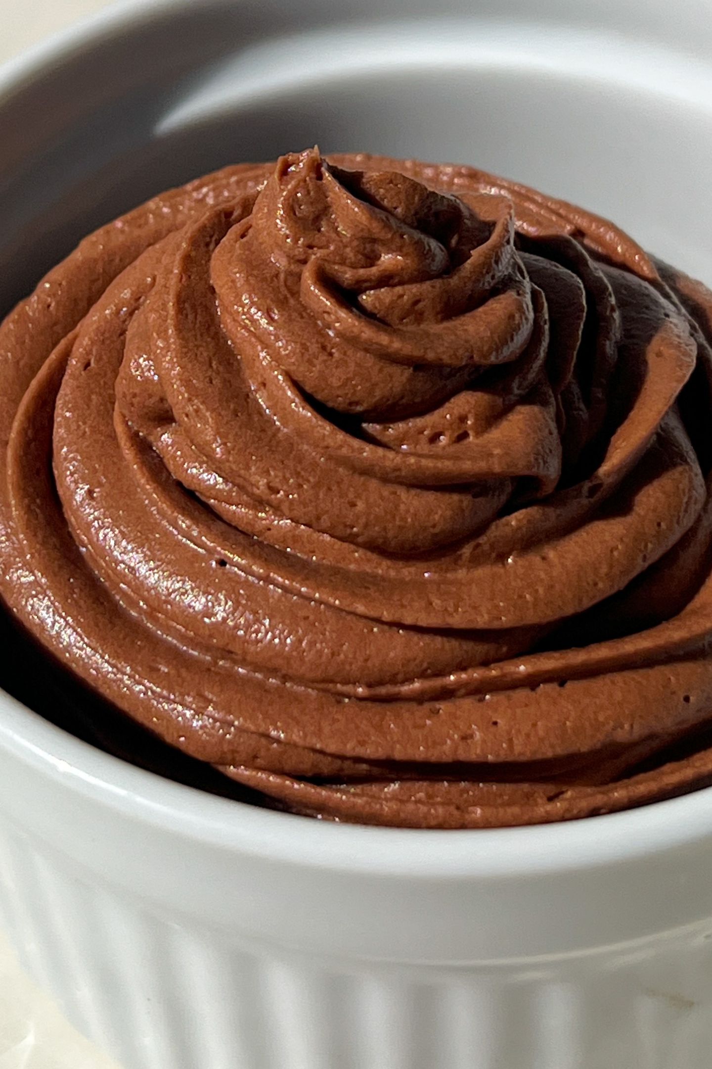 Whipped chocolate frosting piped into a bowl.