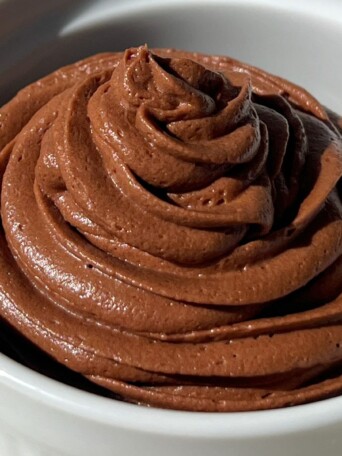 Smooth and Creamy Chocolate Frosting made with cream cheese piped into a bowl.