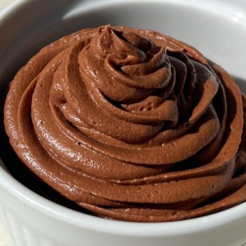 Smooth and Creamy Chocolate Frosting made with cream cheese piped into a bowl.