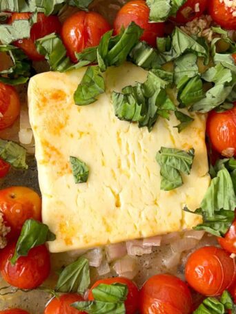 baked feta and tomatoes in a baking dish with fresh basil