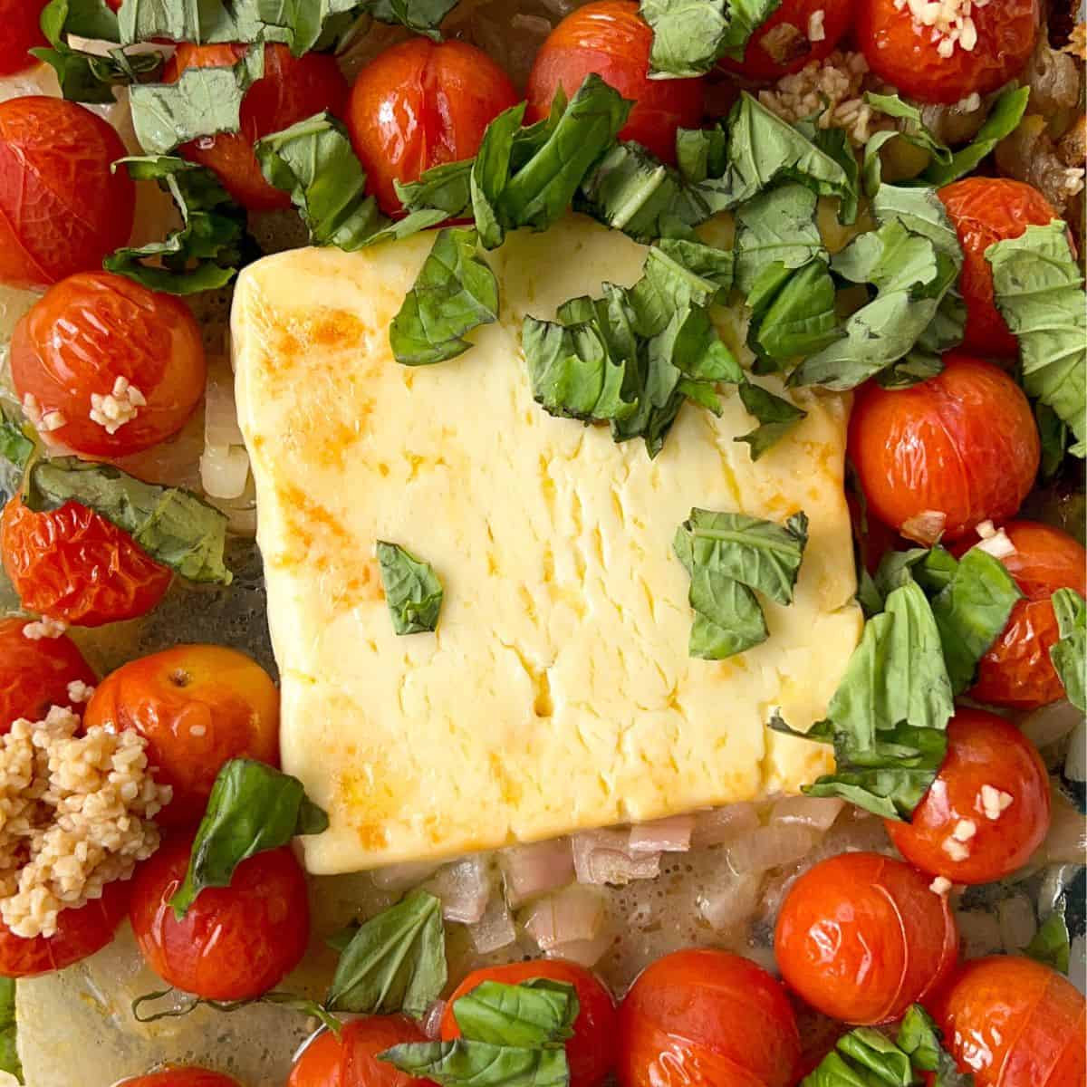 baked feta and tomatoes in a baking dish with fresh basil