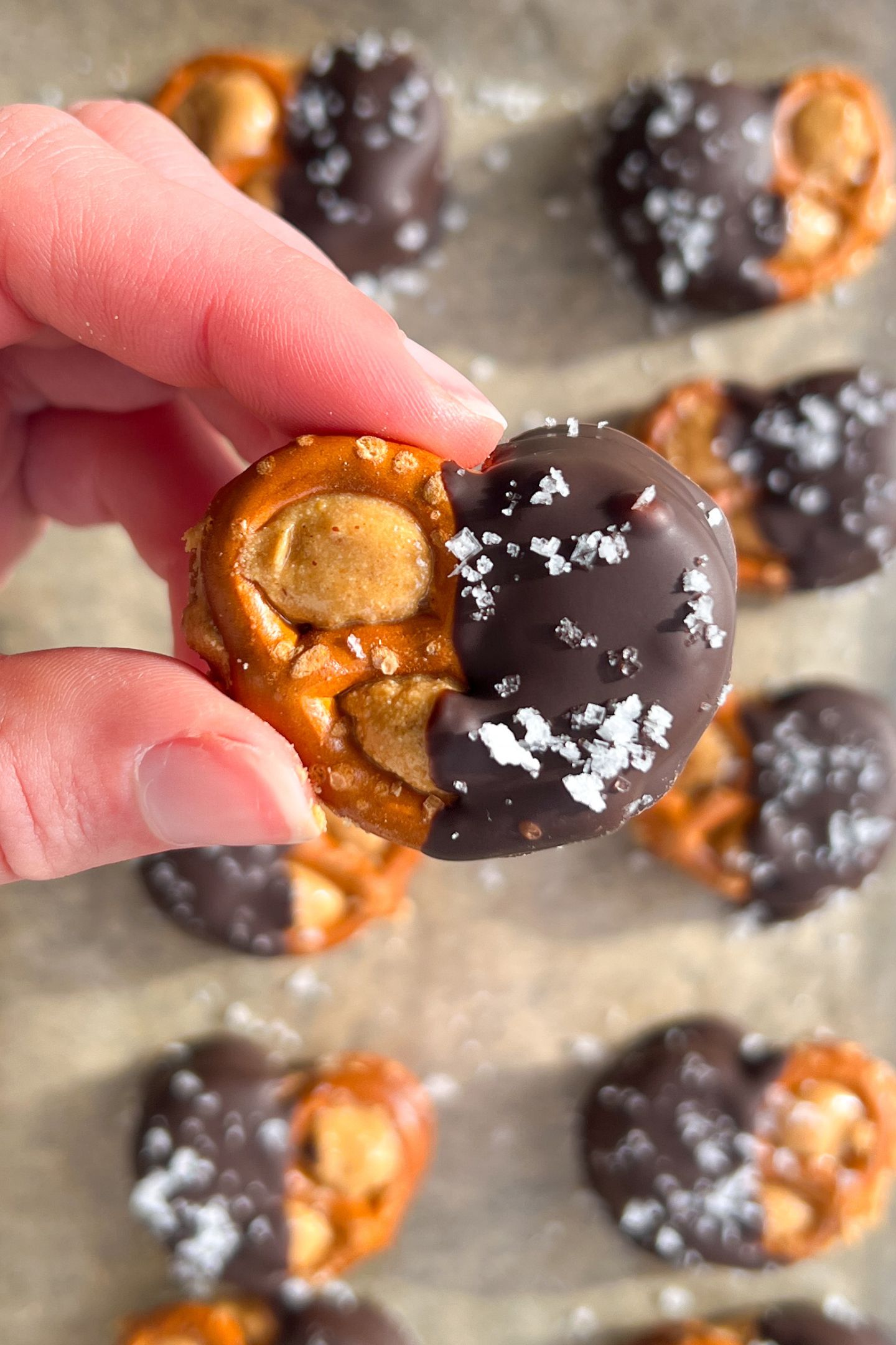 Holding a Peanut Butter Pretzel covered in chocolate and sea salt.
