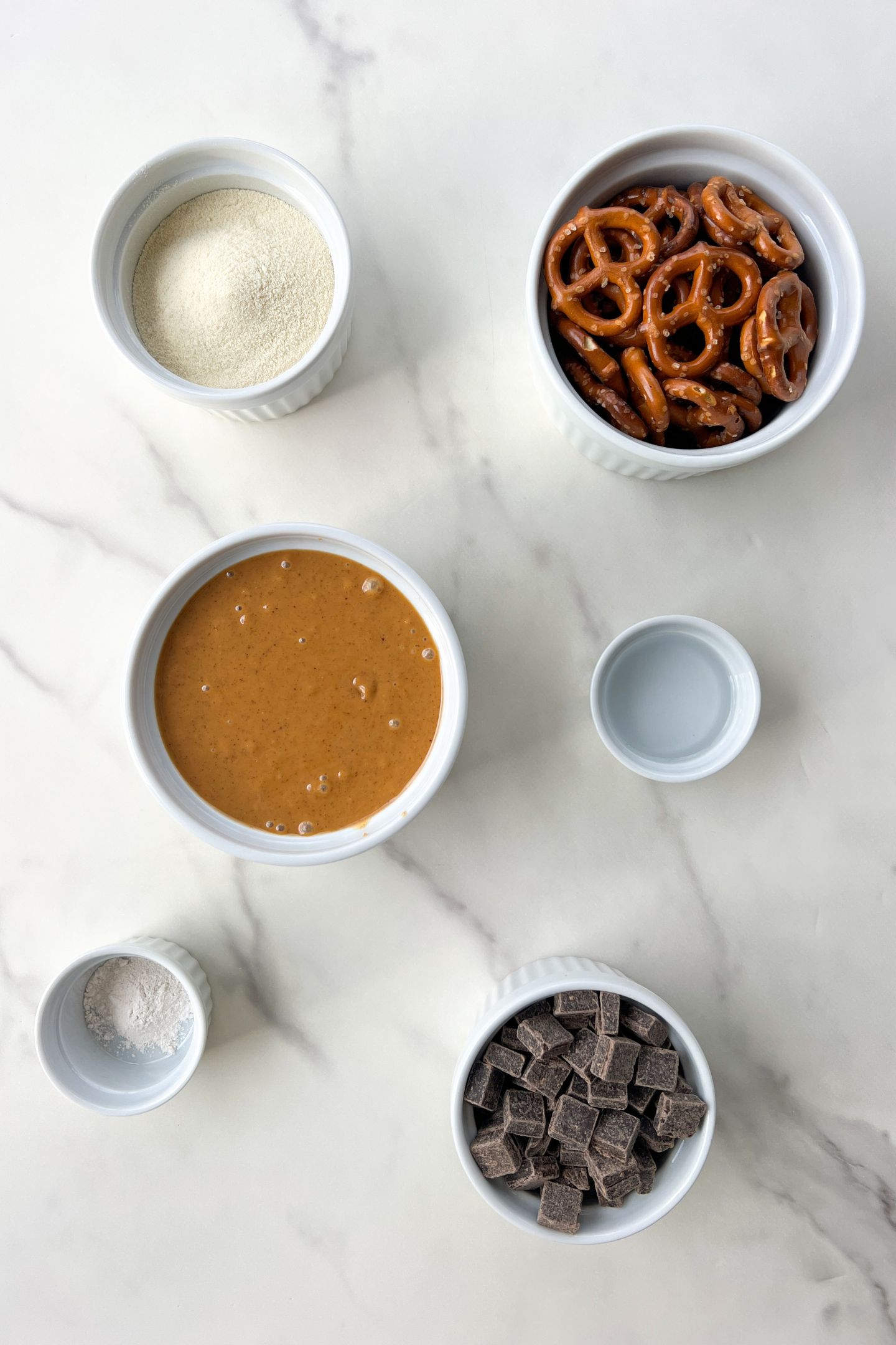 Measured out ingredients in bowls to make pretzel bites covered in chocolate.