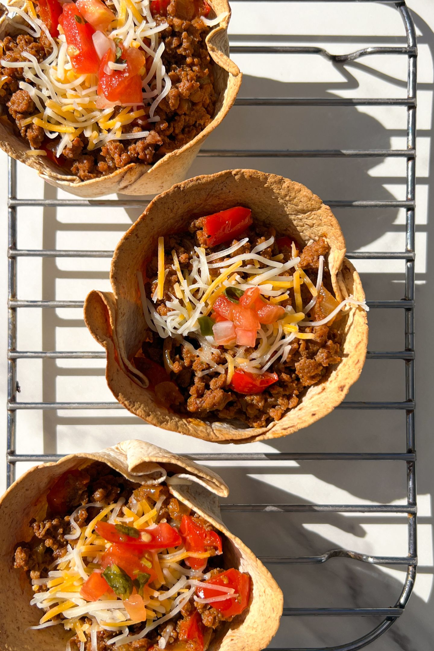 Beef taco cups on a cooling rack.