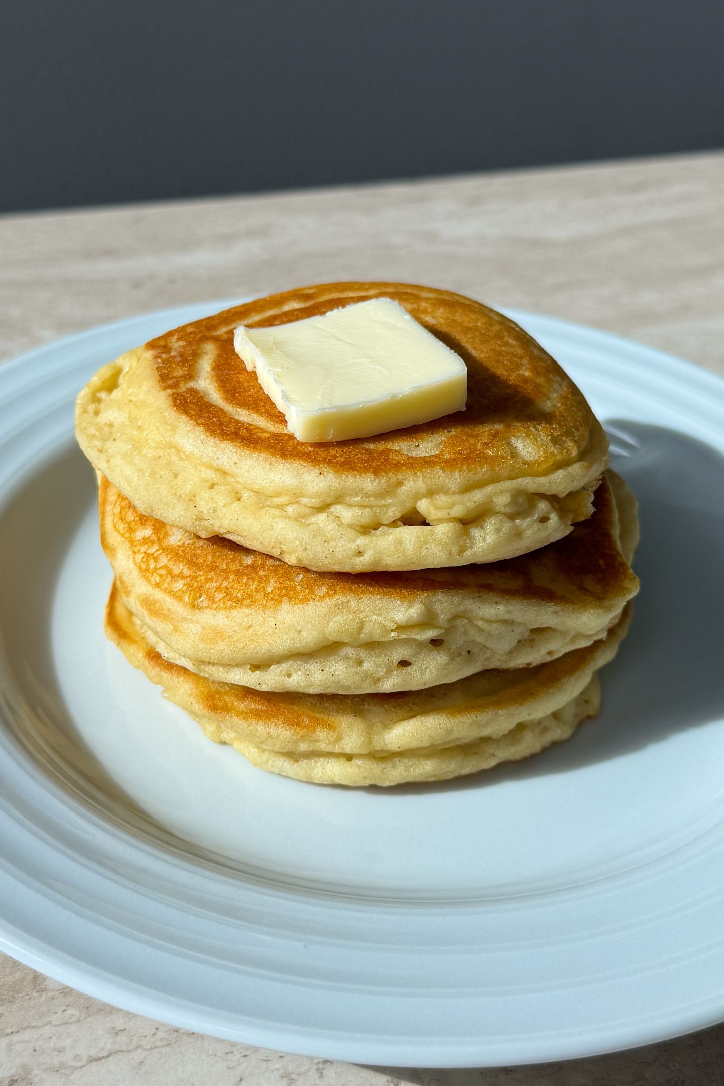 Stack of buttermilk pancakes topped with butter.