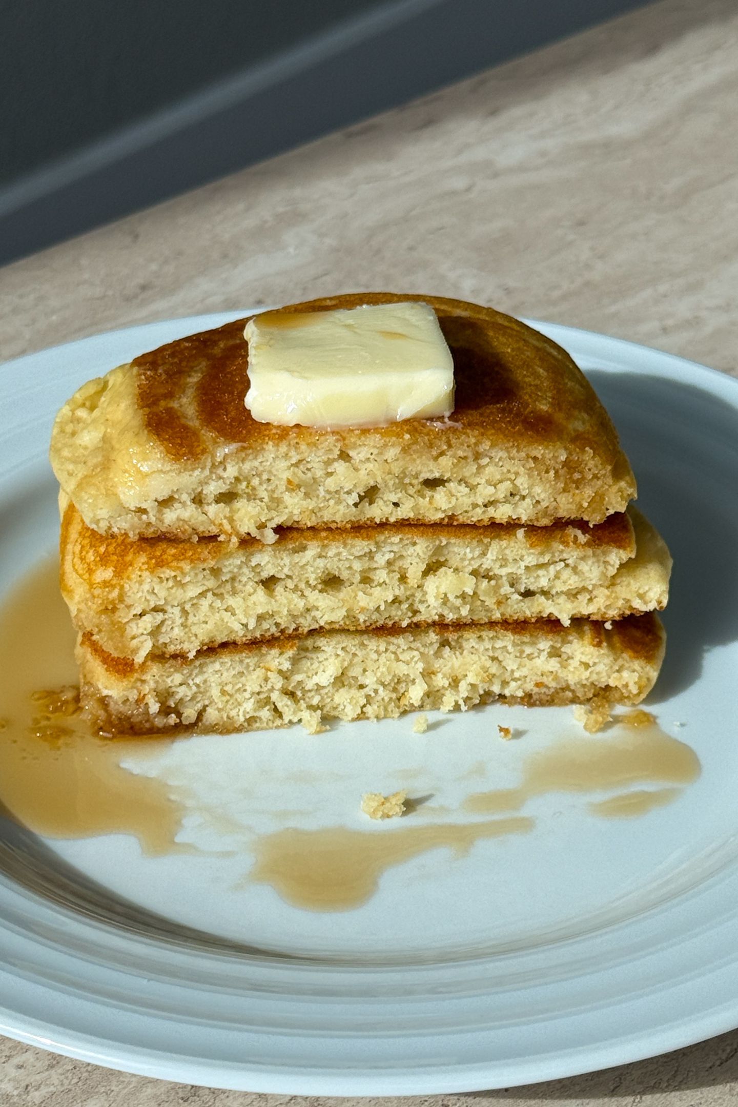 Stack of buttermilk pancakes topped with butter and syrup.