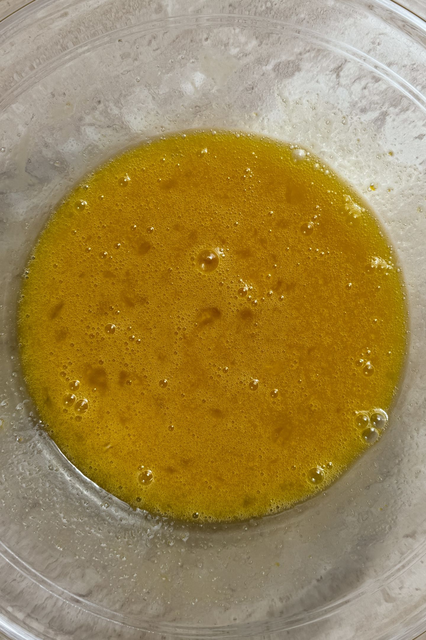 Whisked eggs, vanilla extract and sugar mixed together in a bowl.