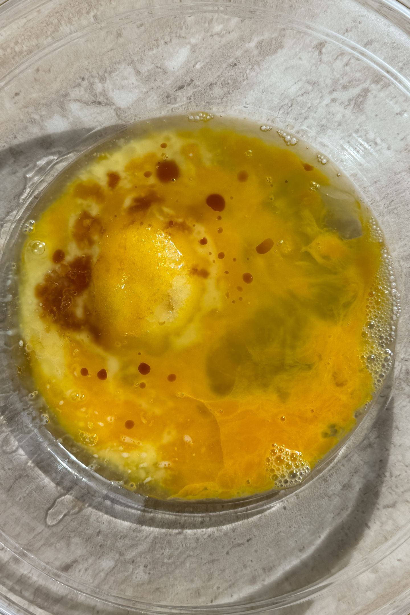 Whisked eggs, vanilla extract and sugar in a bowl.