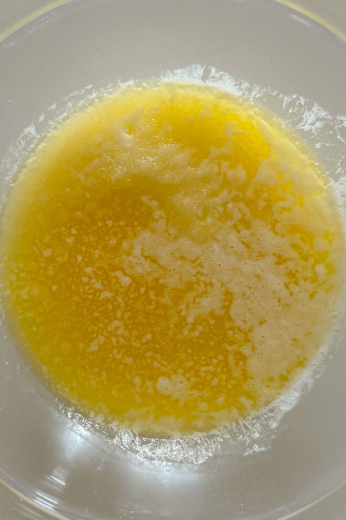 Granulated sugar in a mixing bowl topped with hot, melted butter.